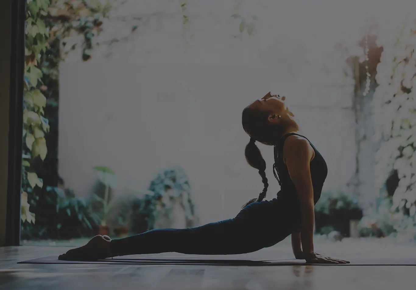 A woman doing yoga with plants in the background. 