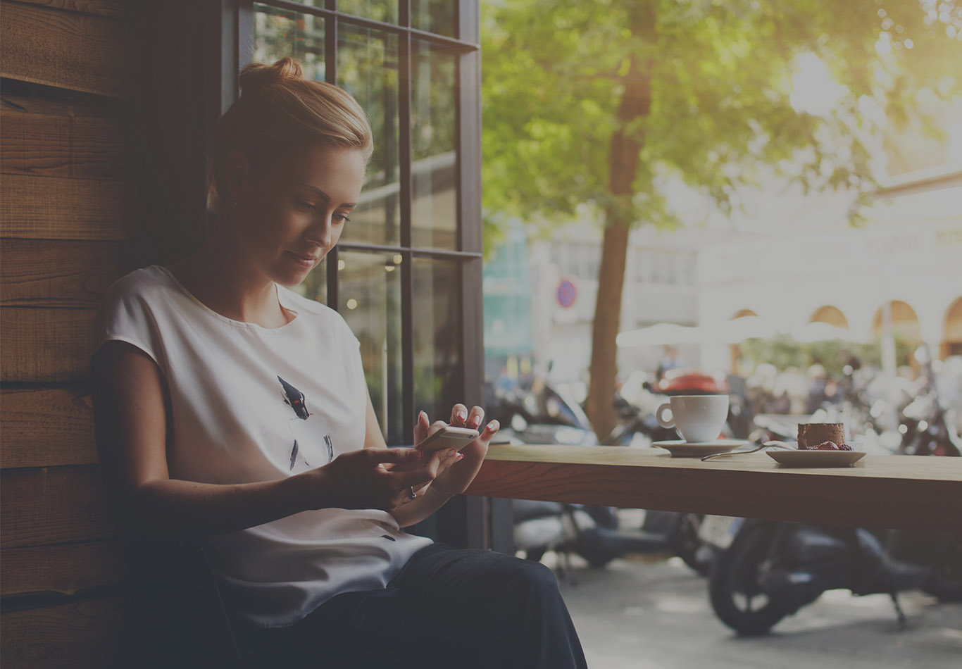 A woman with blonde hair is sitting looking at her phone. 
